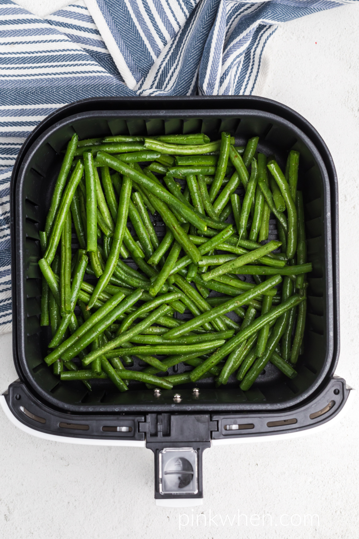 fresh green beans in air fryer basket ready to cook. 