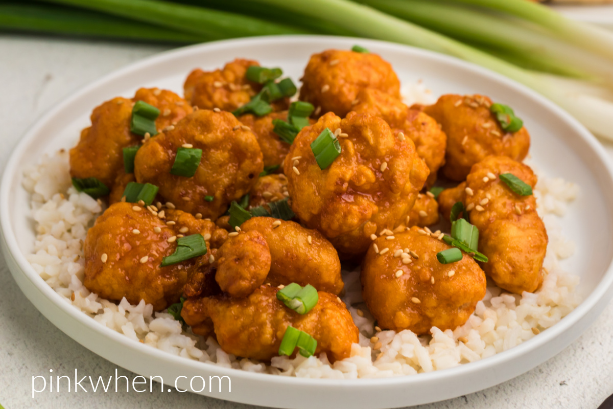 Air fryer orange chicken topped with green onion tops and sesame seeds and served over white rice. 