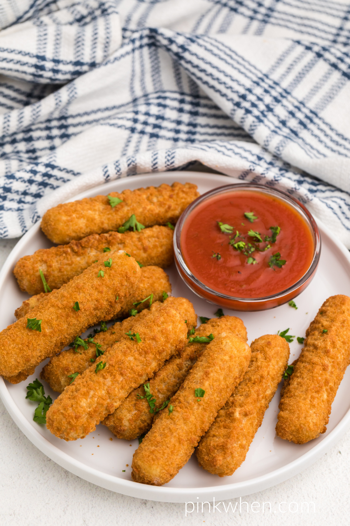 Mozzarella sticks made in the air fryer and on a white plate. 