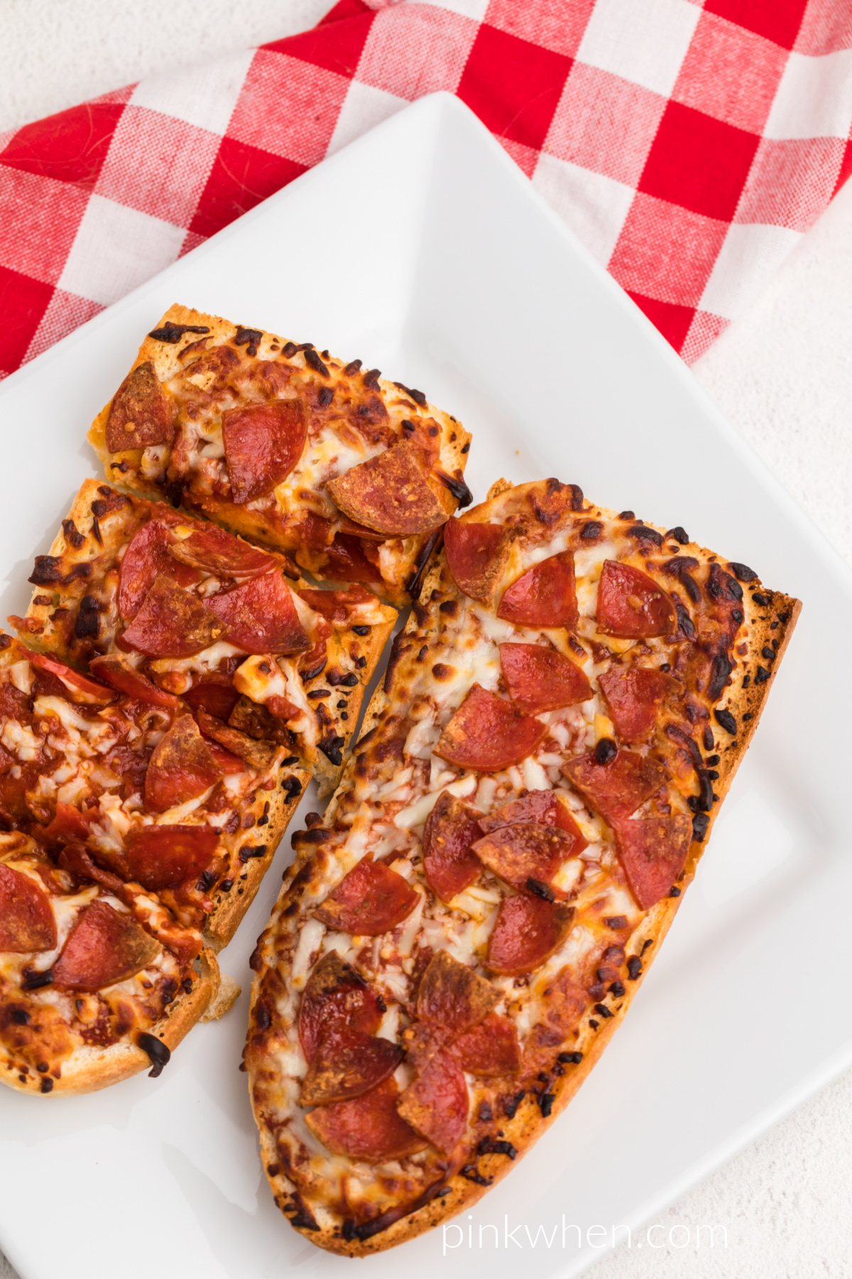 Air fryer french bread pizzas fully cooked and served on a white plate. 