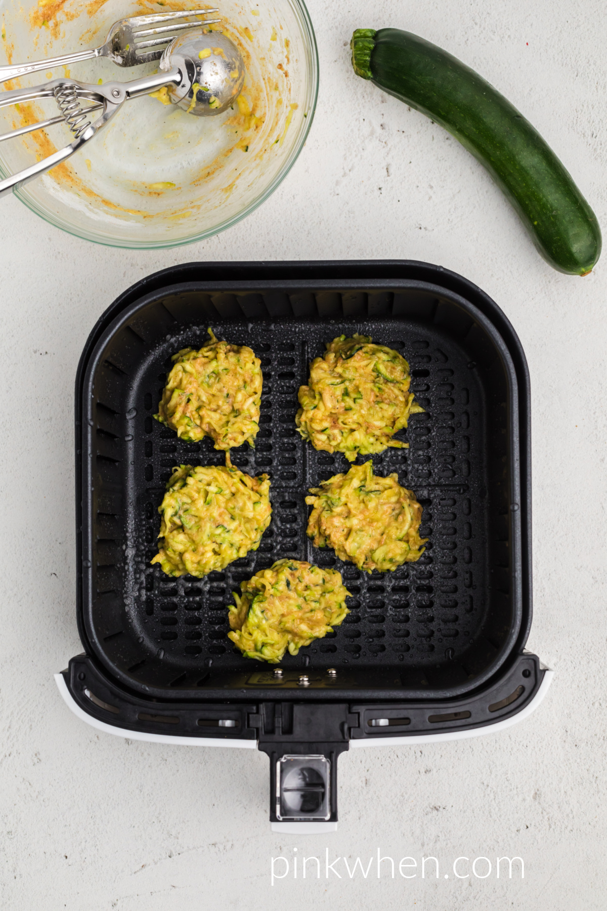 Zucchini mixture scooped onto the prepared air fryer basket, ready to cook.