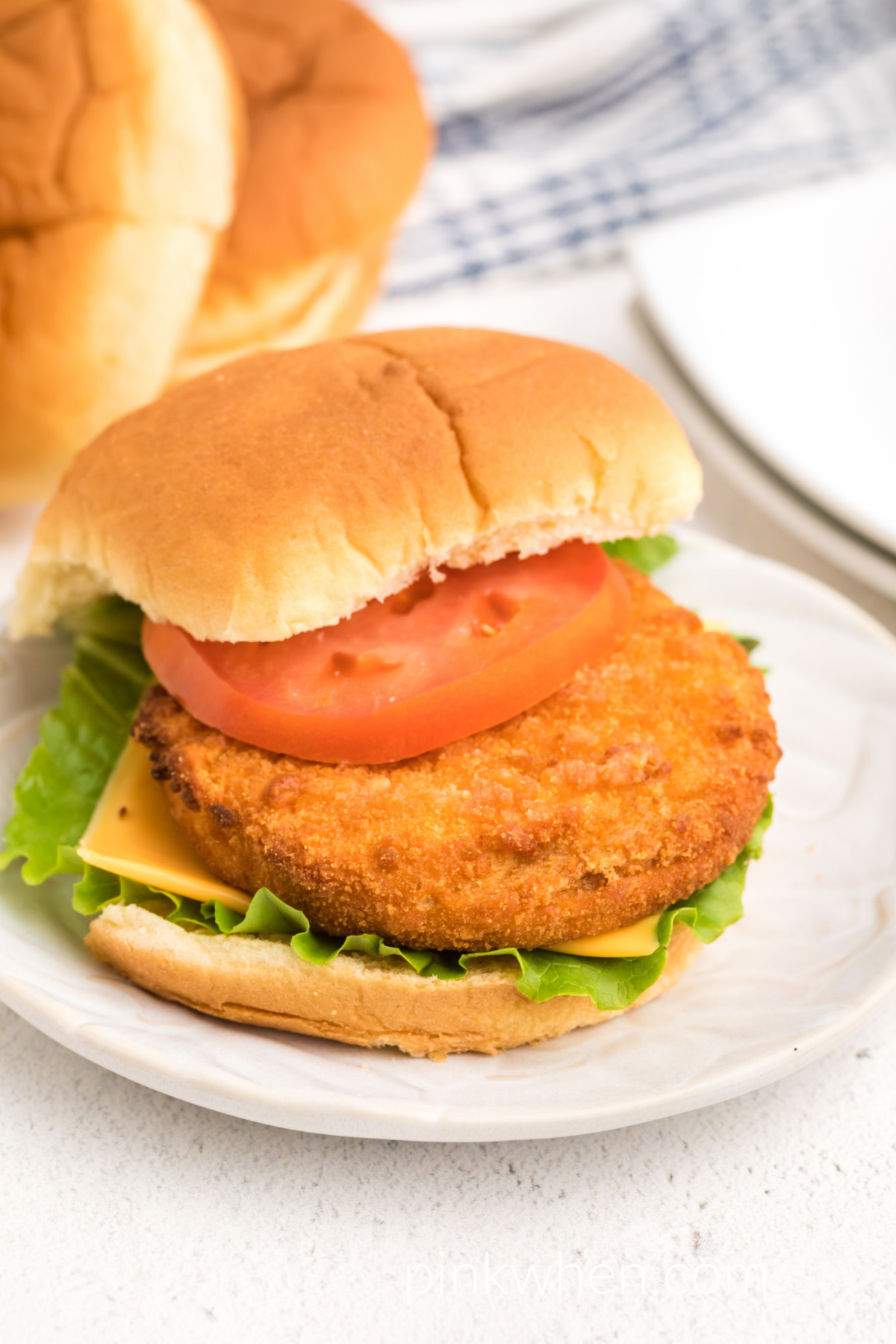 Fully cooked crispy chicken pattie sandwich that was made in the air fryer - served on a white plate. 