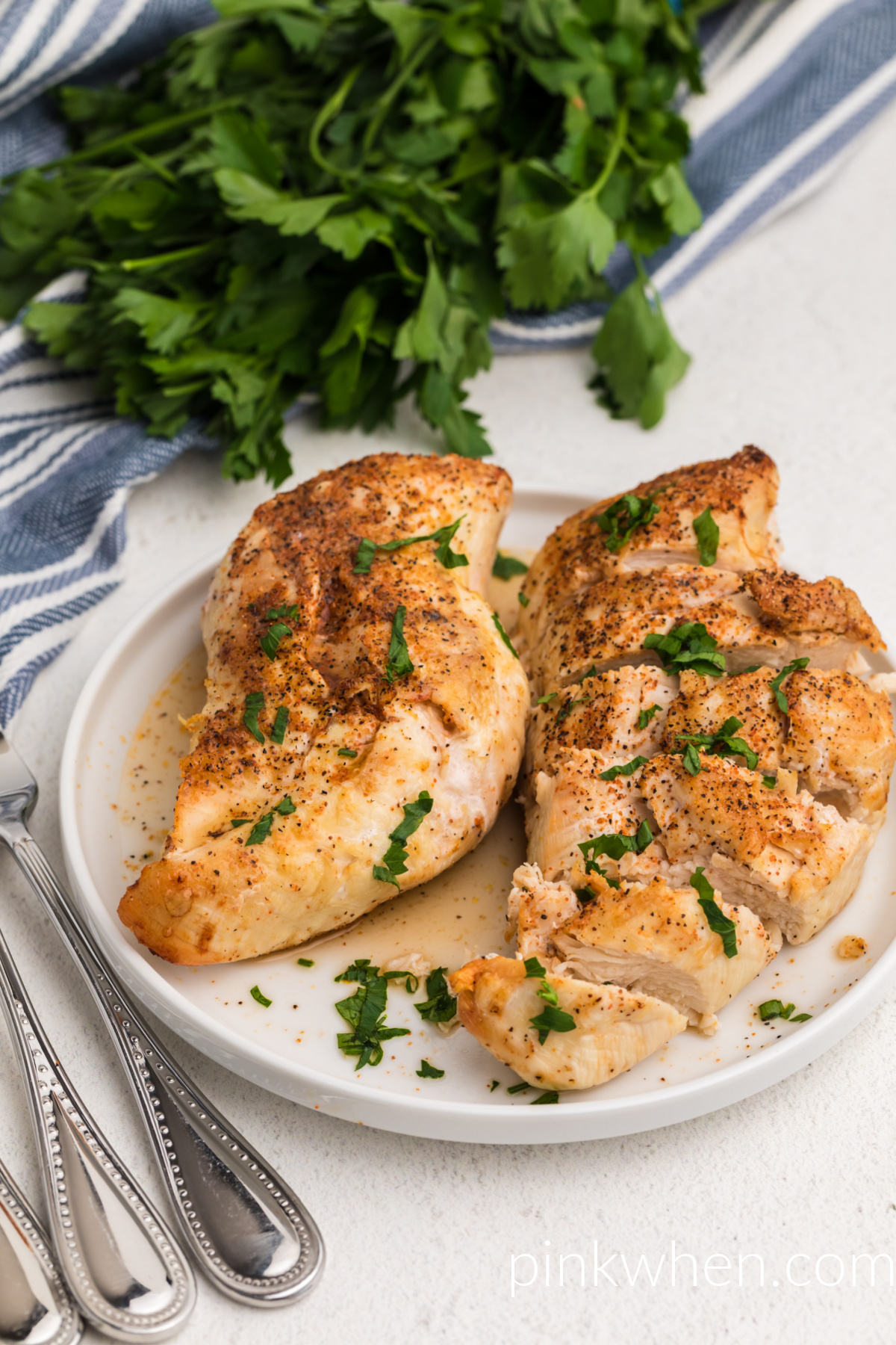 Juicy chicken breasts cooked from frozen in the air fryer and served on a white plate. 