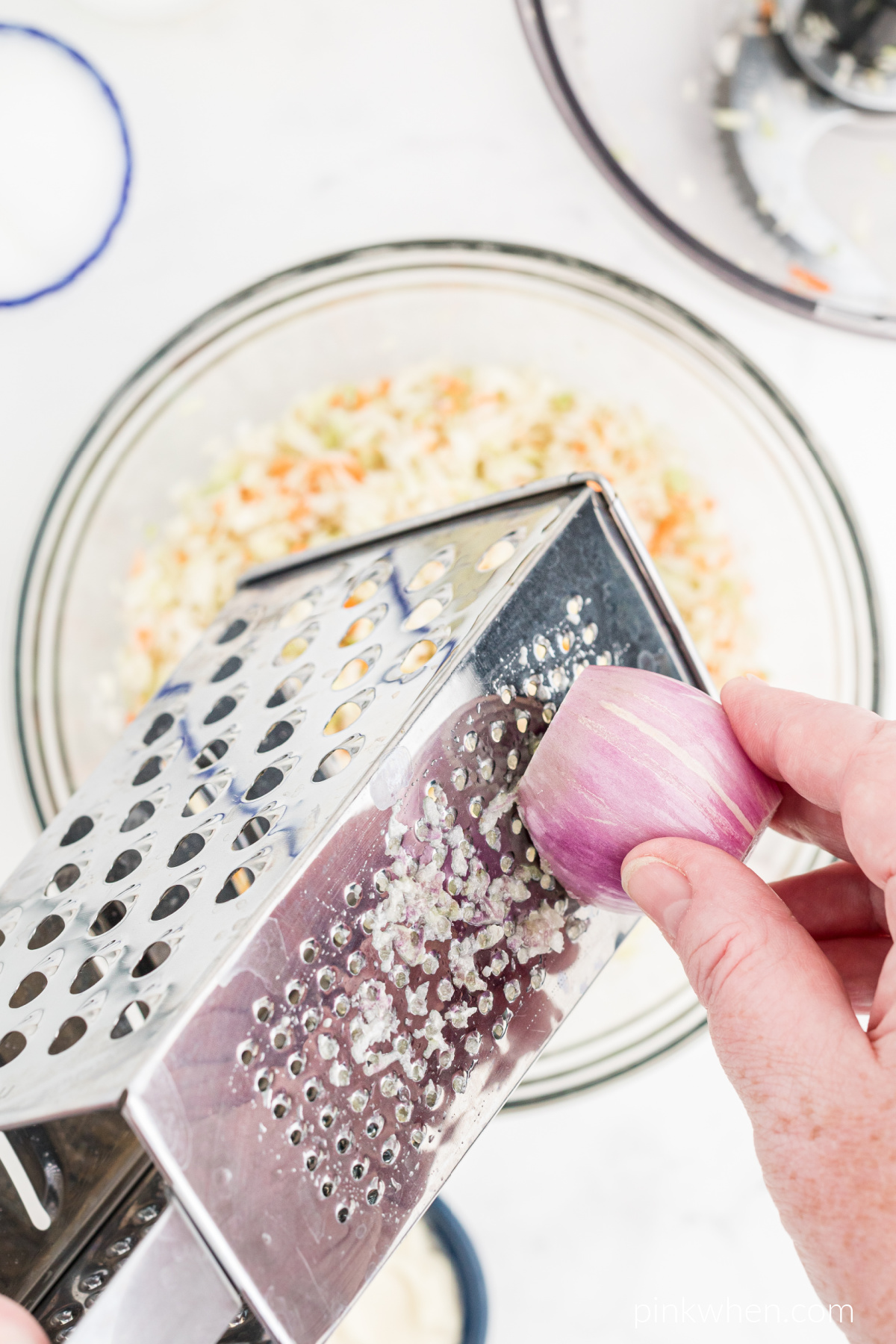 Grating of the shallot into the coleslaw mixture.