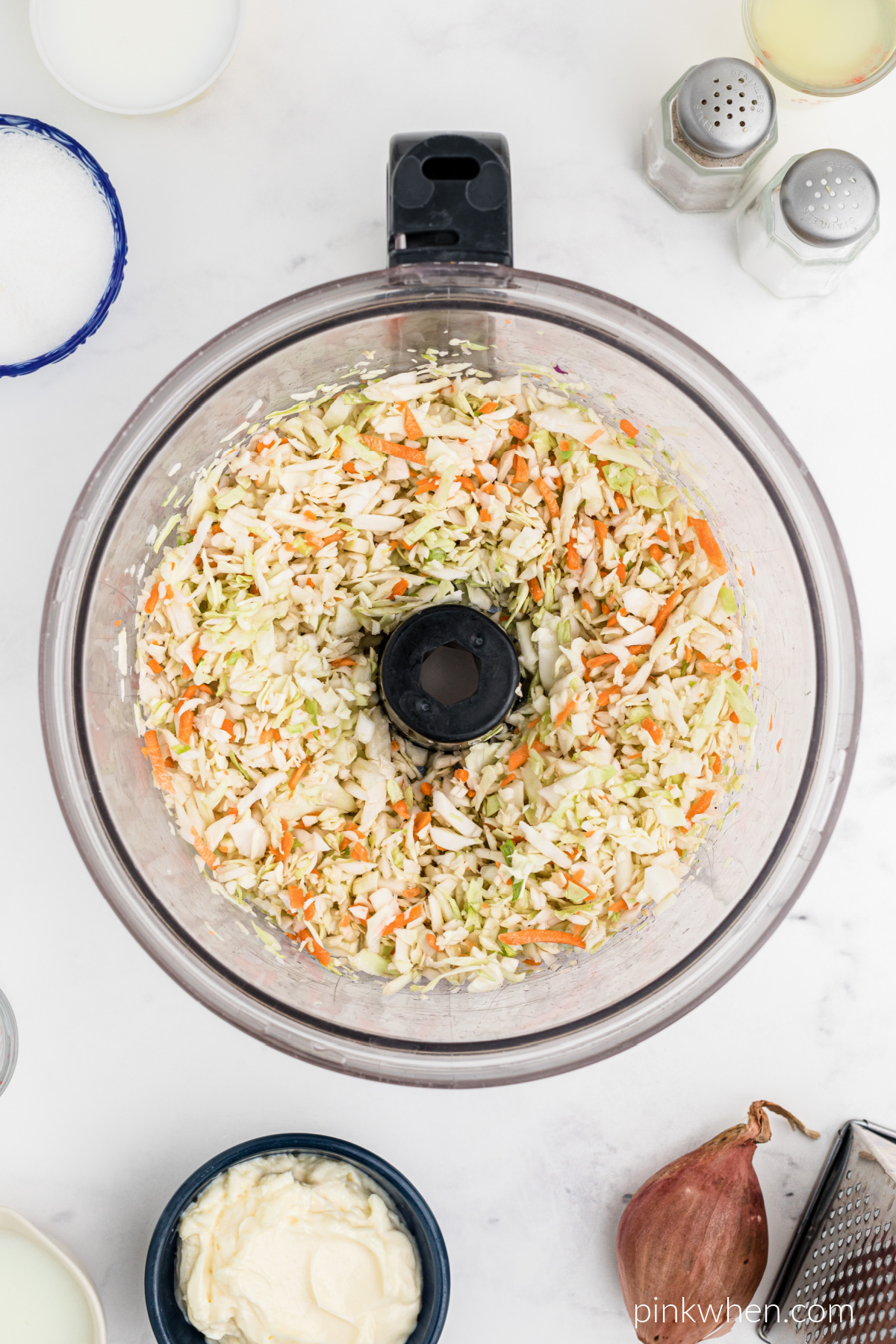 Coleslaw ingredients being added to a food processor.