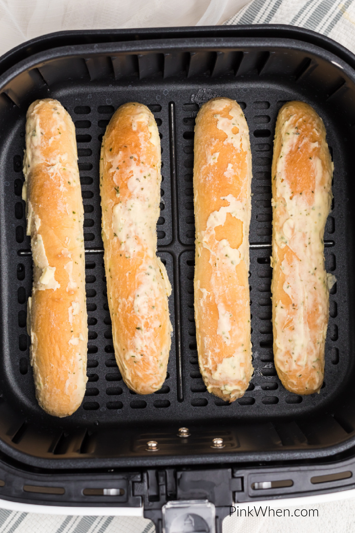Frozen breadsticks in a single layer in the basket of the air fryer.