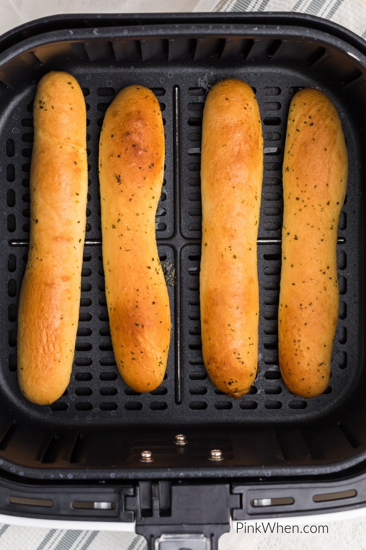 Air fried breadsticks made from frozen, fully cooked and in the basket of the air fryer.