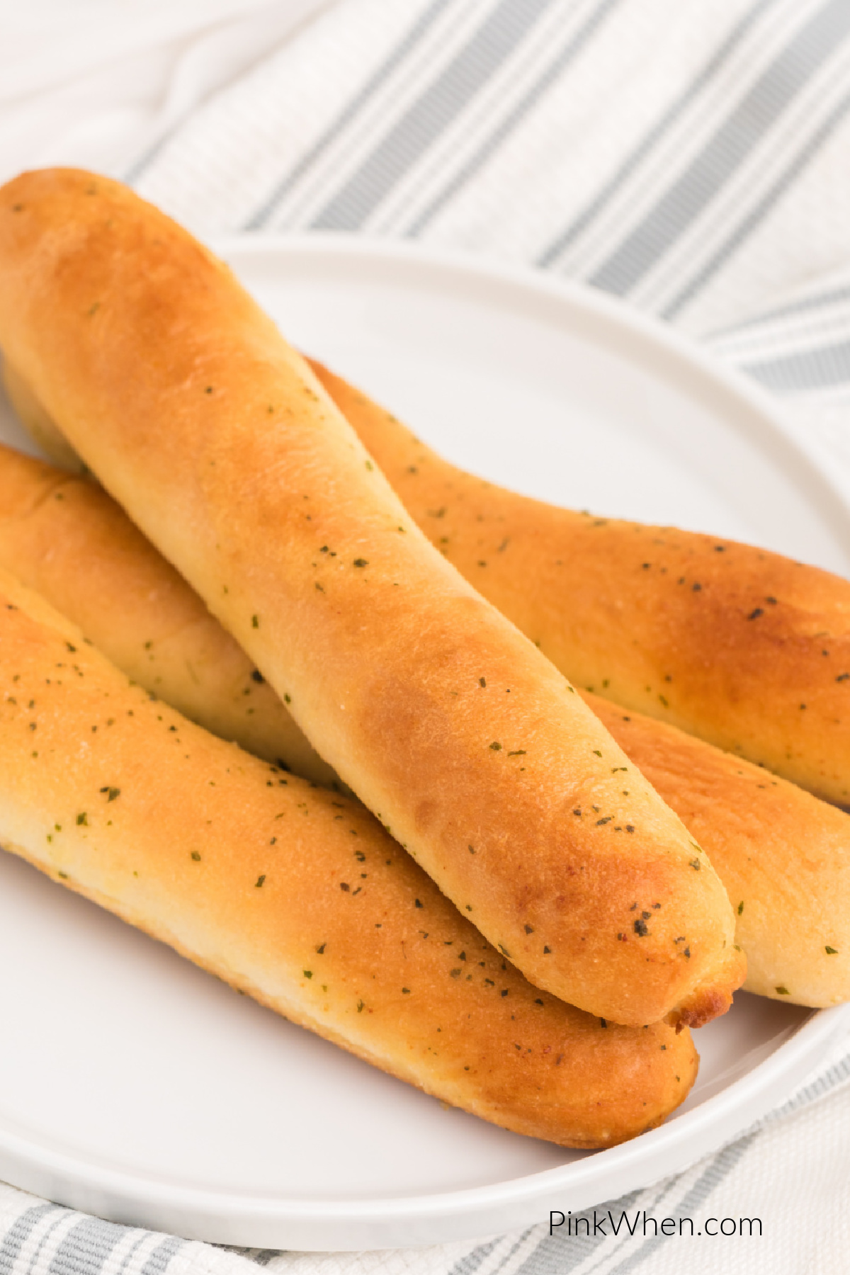 Close up of breadsticks made in the air fryer from frozen on a white plate.