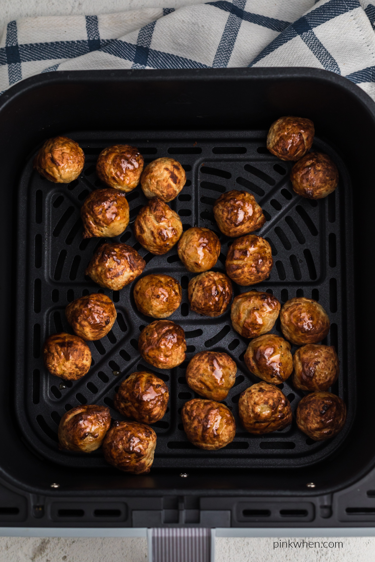 Juicy, cooked frozen meatballs in the air fryer basket, ready to serve.