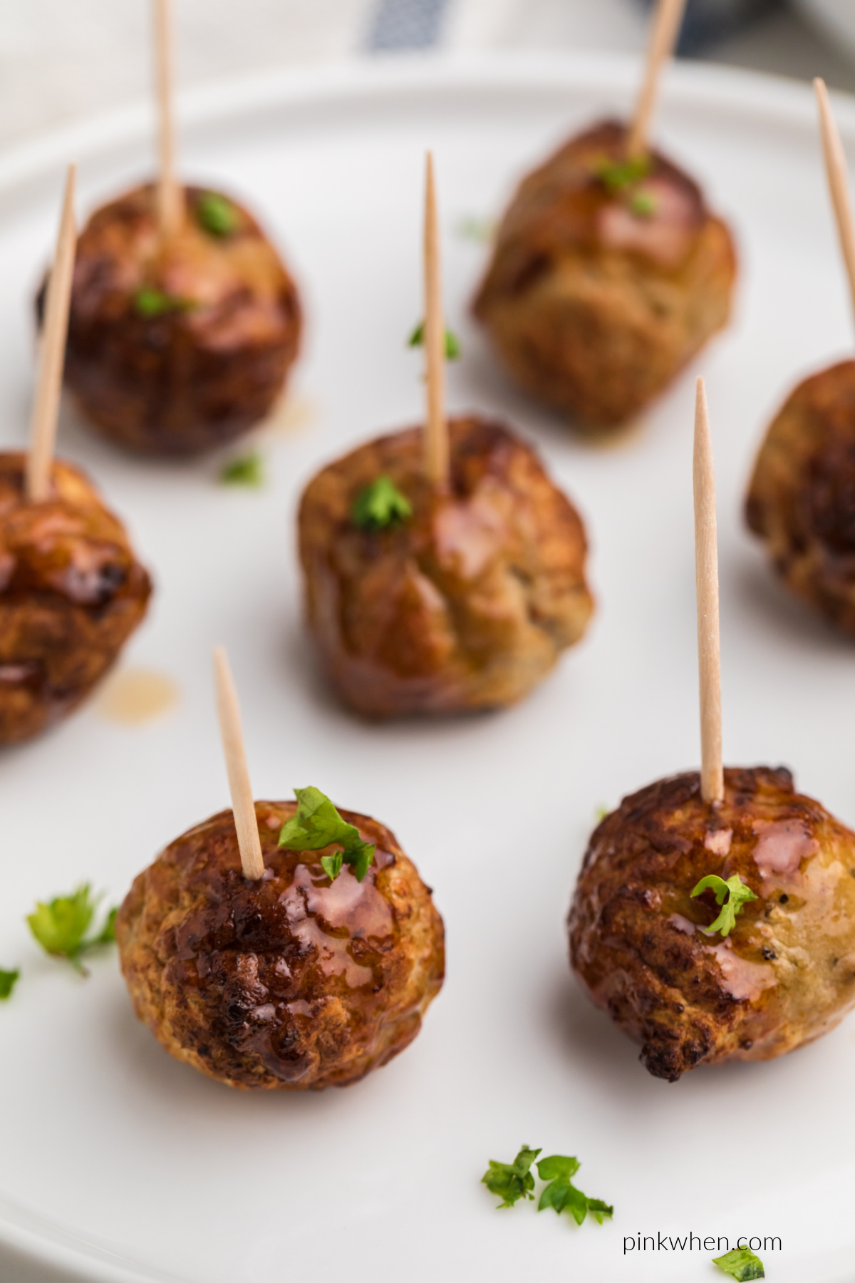 Meatballs made from frozen in the air fryer and served with toothpicks and topped with fresh parsley.