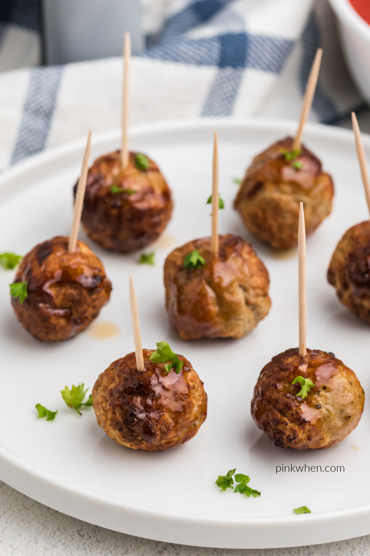 Air fried meatballs on a white plate inserted with toothpicks and ready to serve.