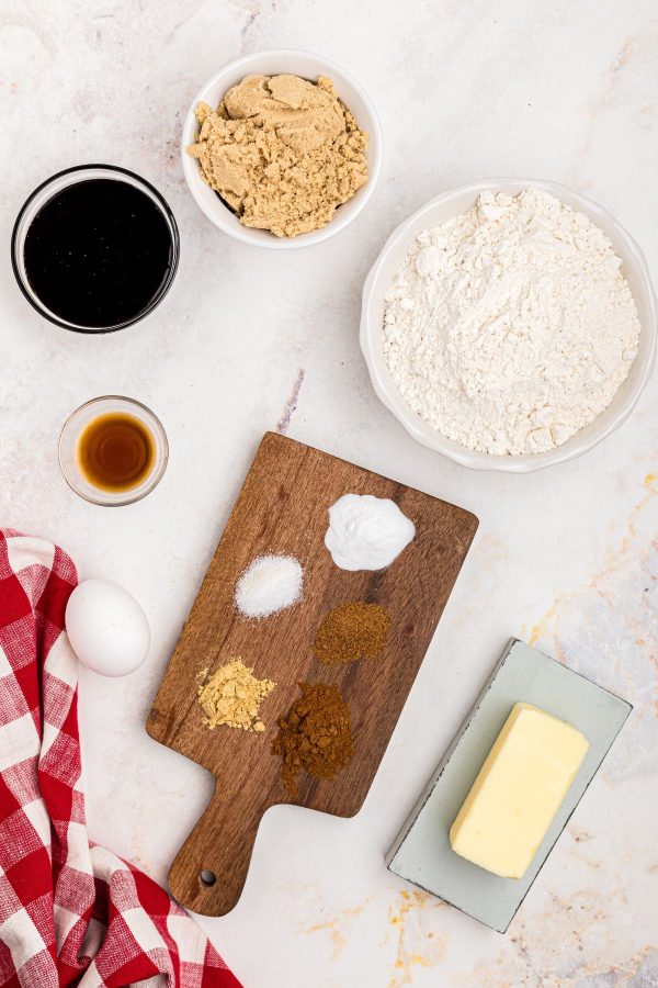 Ingredients needed to make gingerbread cookies on a white marble table. 