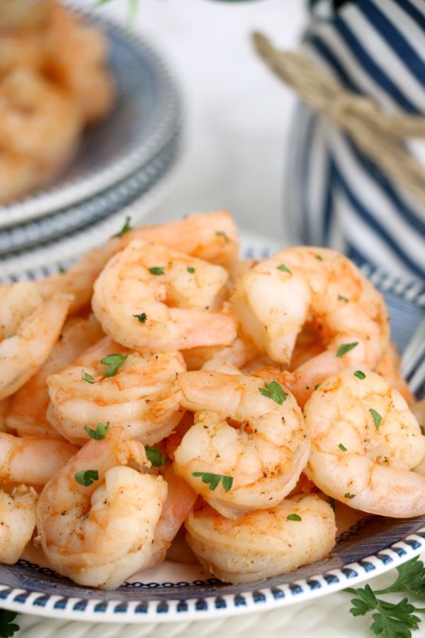 Orange shrimp piled in a white and blue plate, with parsley garnish.