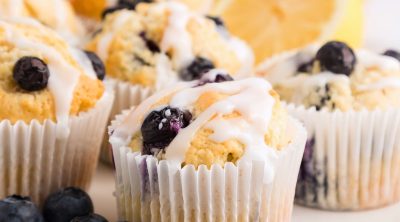 Golden lemon blueberry muffins on a white plate with lemon slices