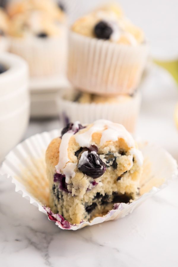 Golden muffin with blueberries and lemon glaze on top.