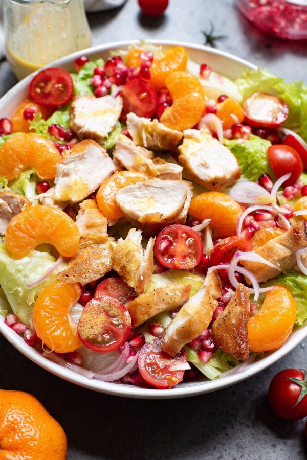 Salad topped with mandarin oranges, cherry tomatoes, sliced chicken and dressing.