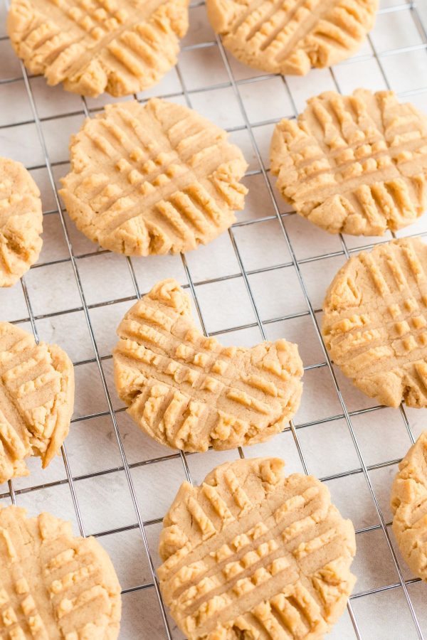 Golden peanut butter cookies spread out on a wire cooling rack