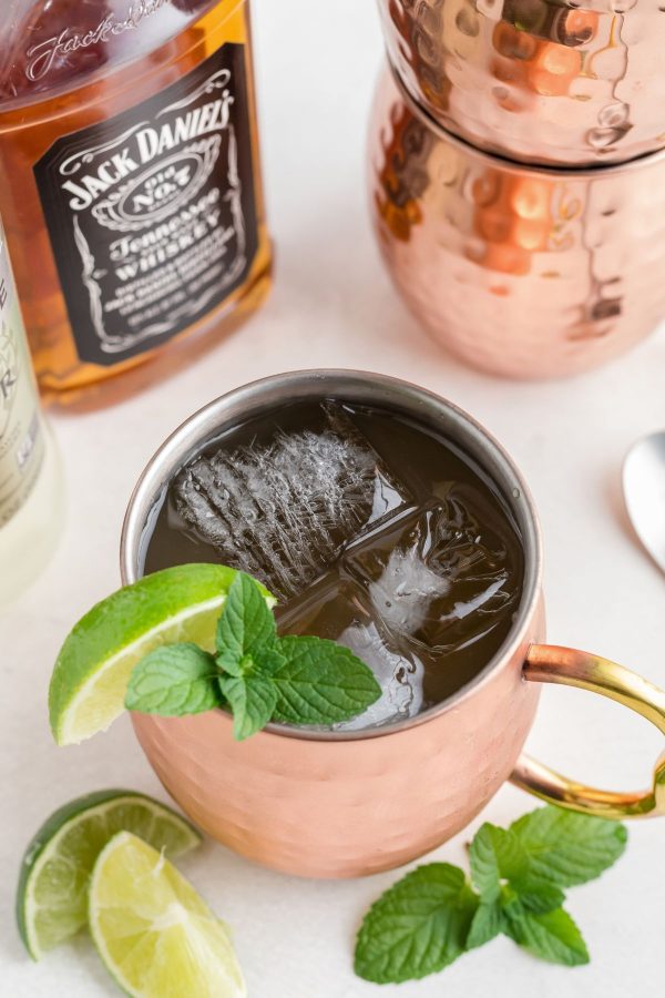 Copper mule mug filled with whiskey, ginger beer, and lime juice with a lime garnish. 