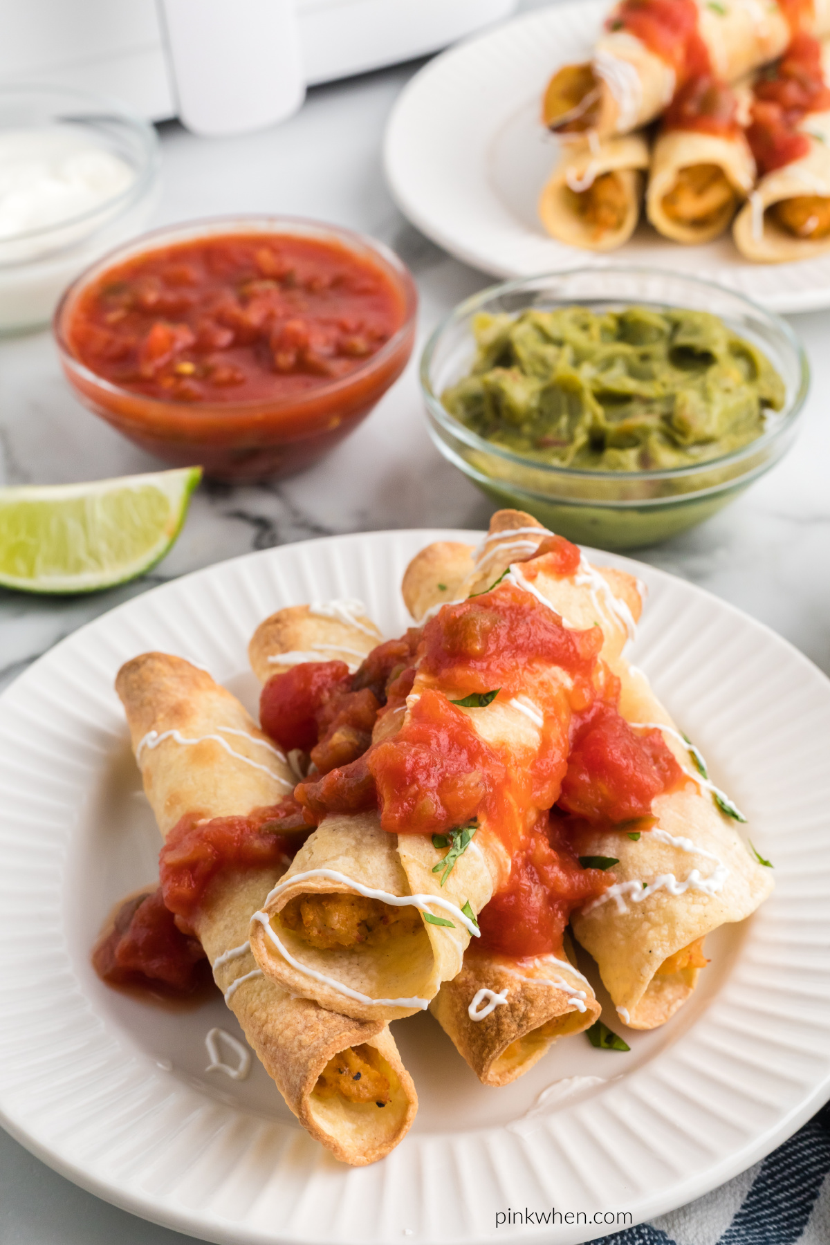 Chicken taquitos topped with sour cream and salsa for serving.