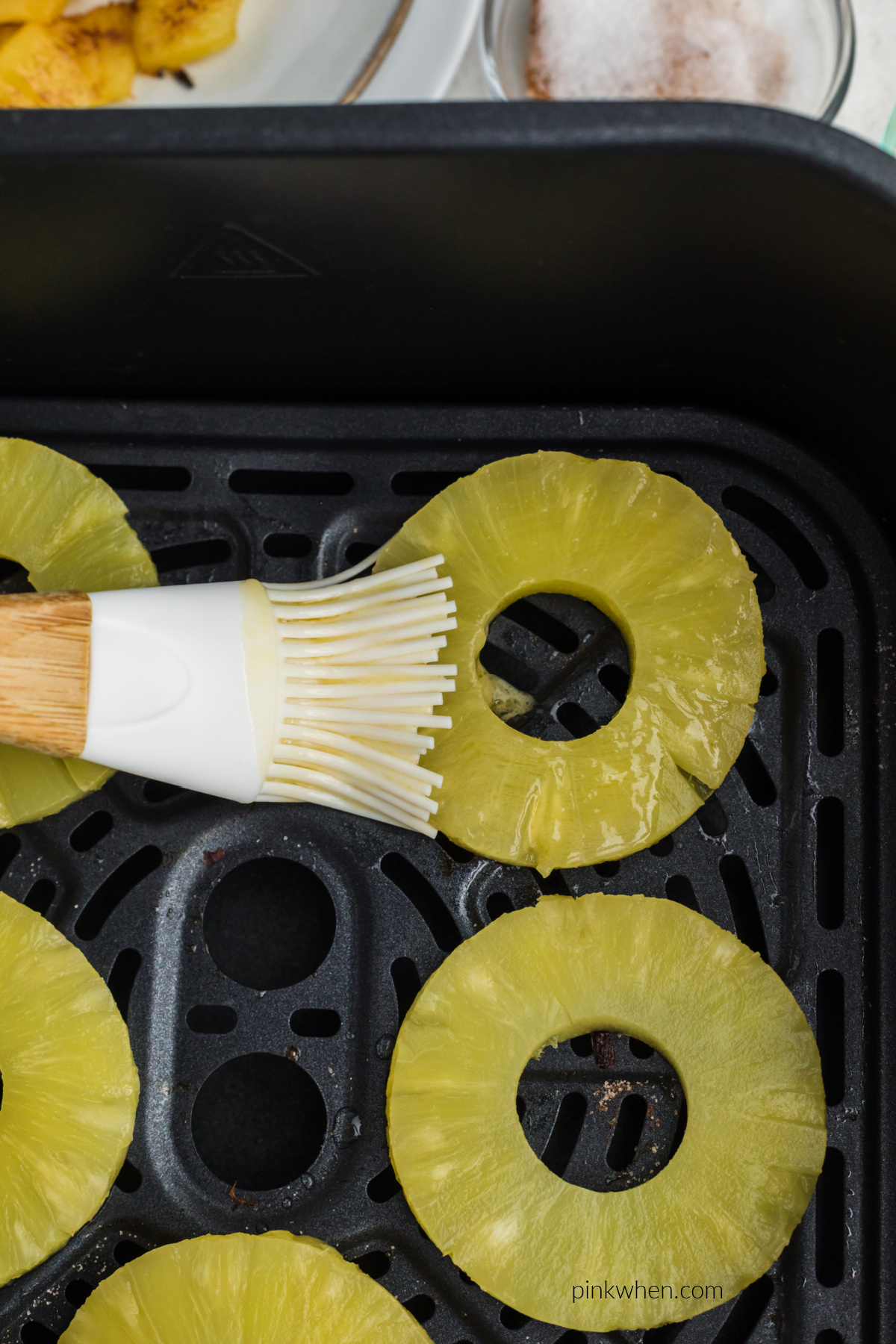 Brushing pineapple rings in butter.