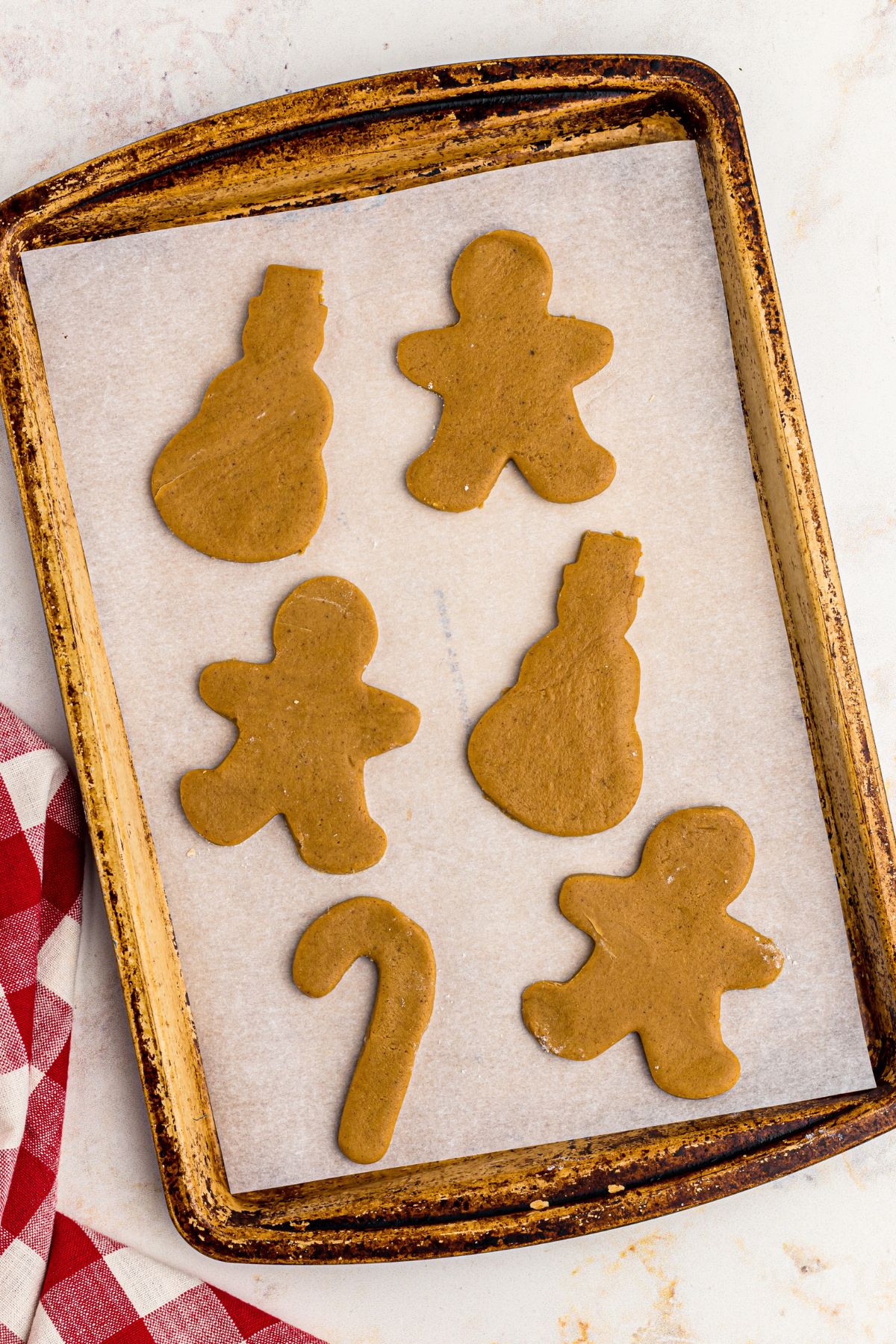 Gingerbread cookies being cooked on a baking sheet. 