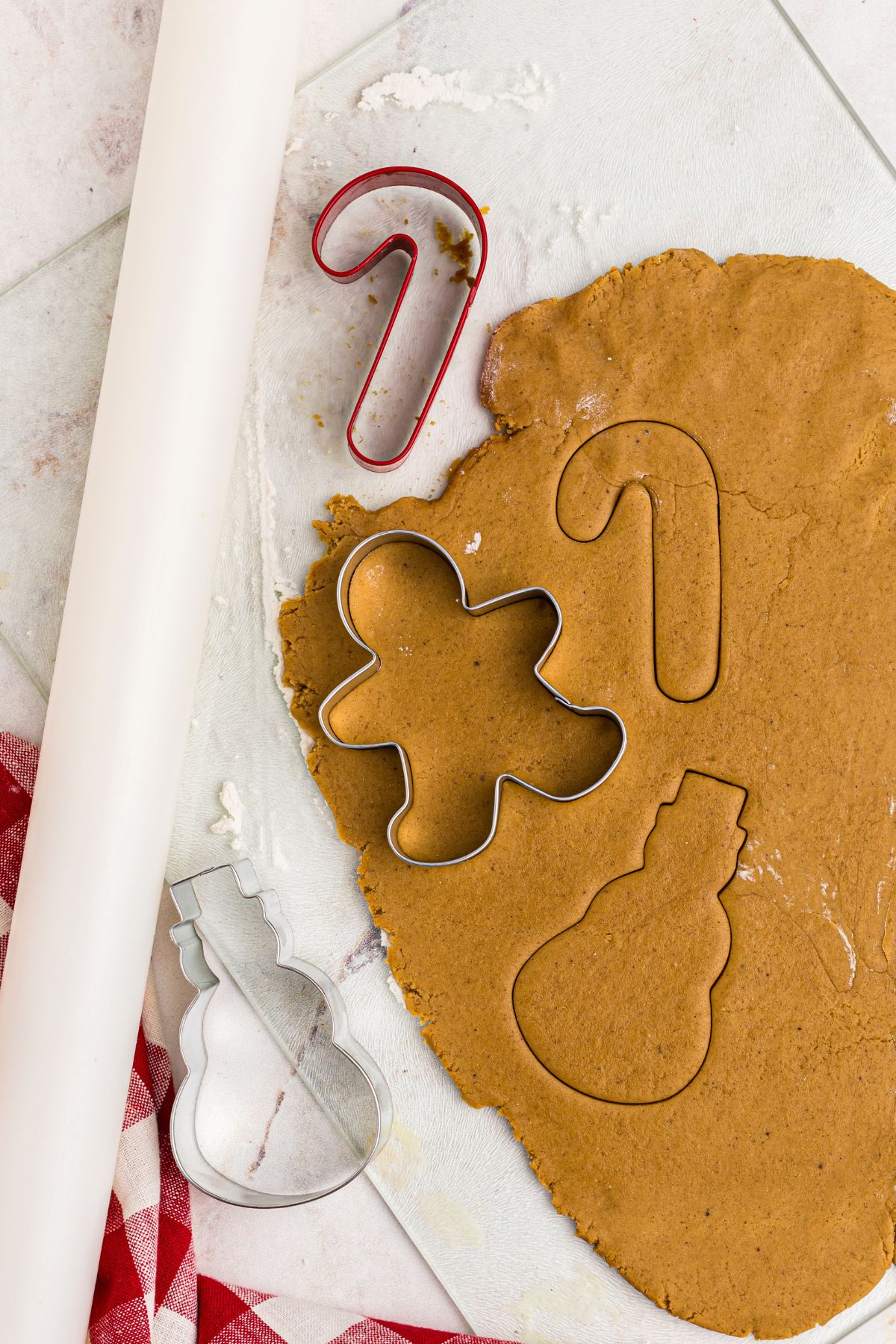 rolled out uncooked gingerbread cookie dough, with cookie cutters 