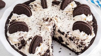 Oreo pie with a slice cut on a white marble table.