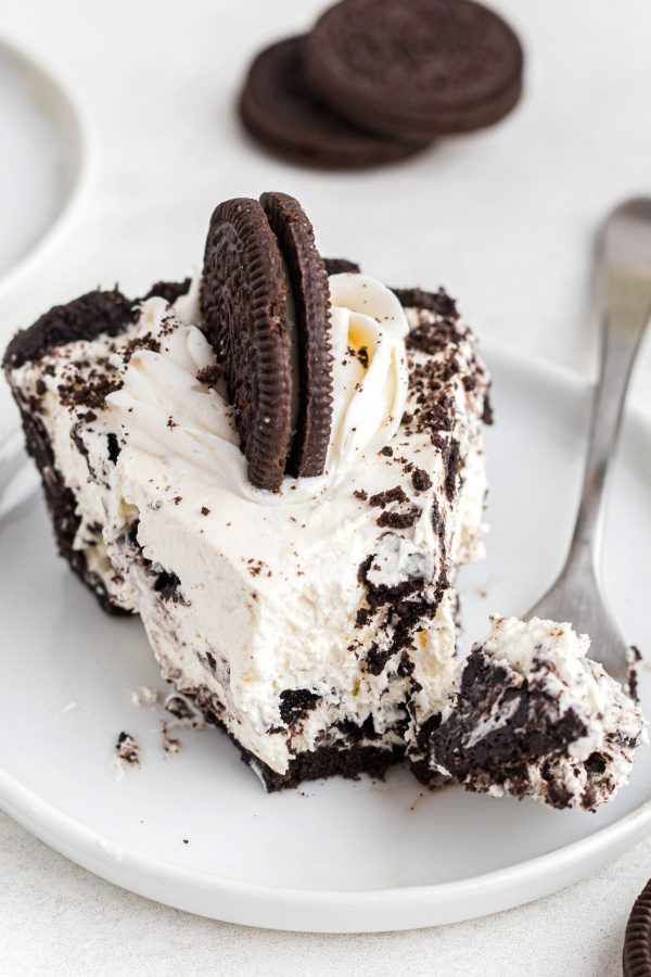 Slice of Oreo pie on a small white plate with a fork bite 