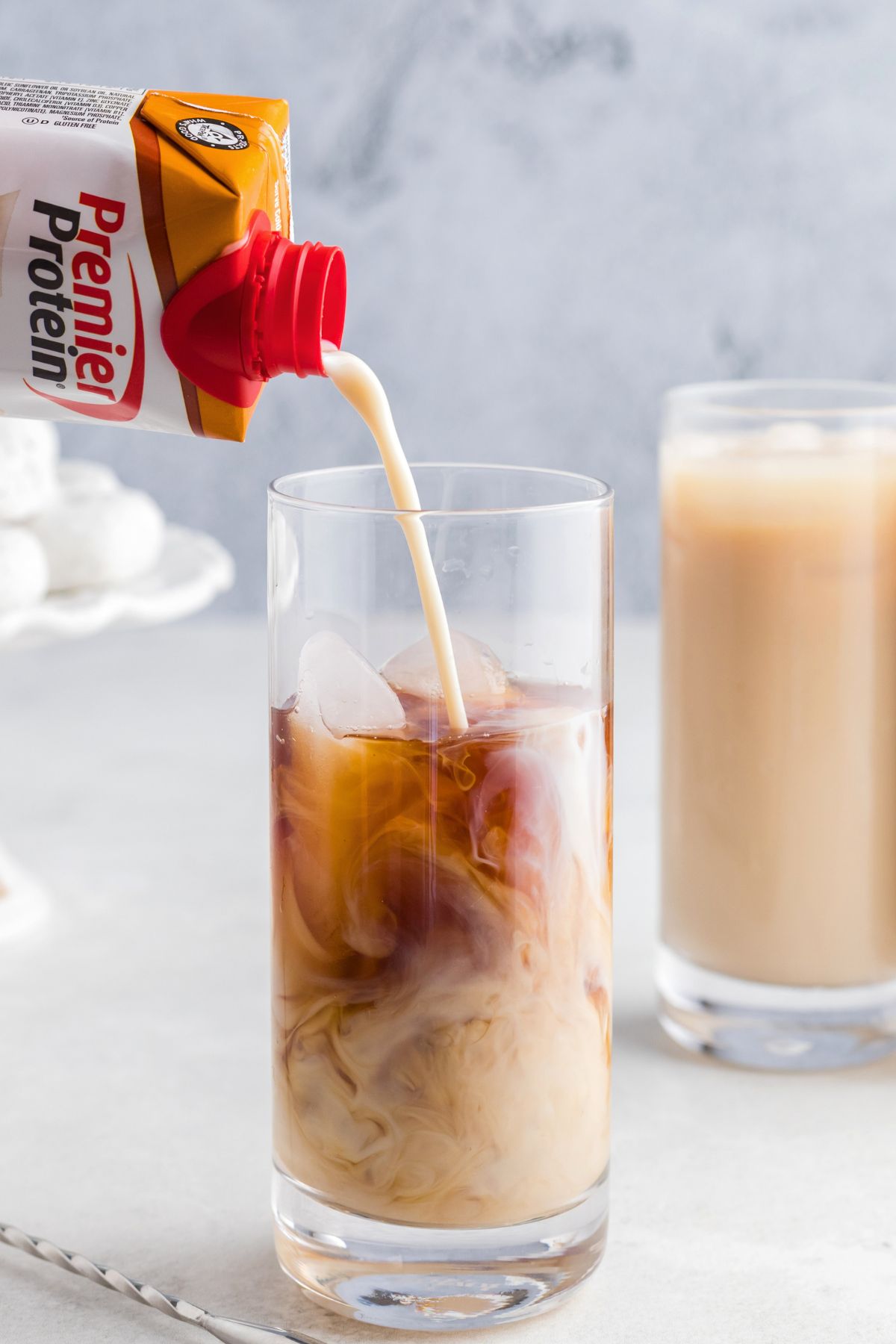 Protein shake being poured over cold coffee and ice cubes.