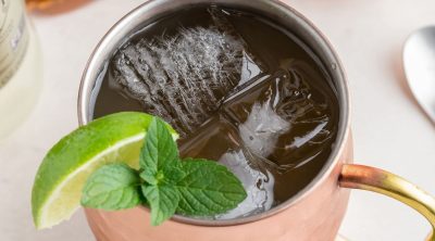 Copper mule mug filled with whiskey, ginger beer, and lime juice with a lime garnish.