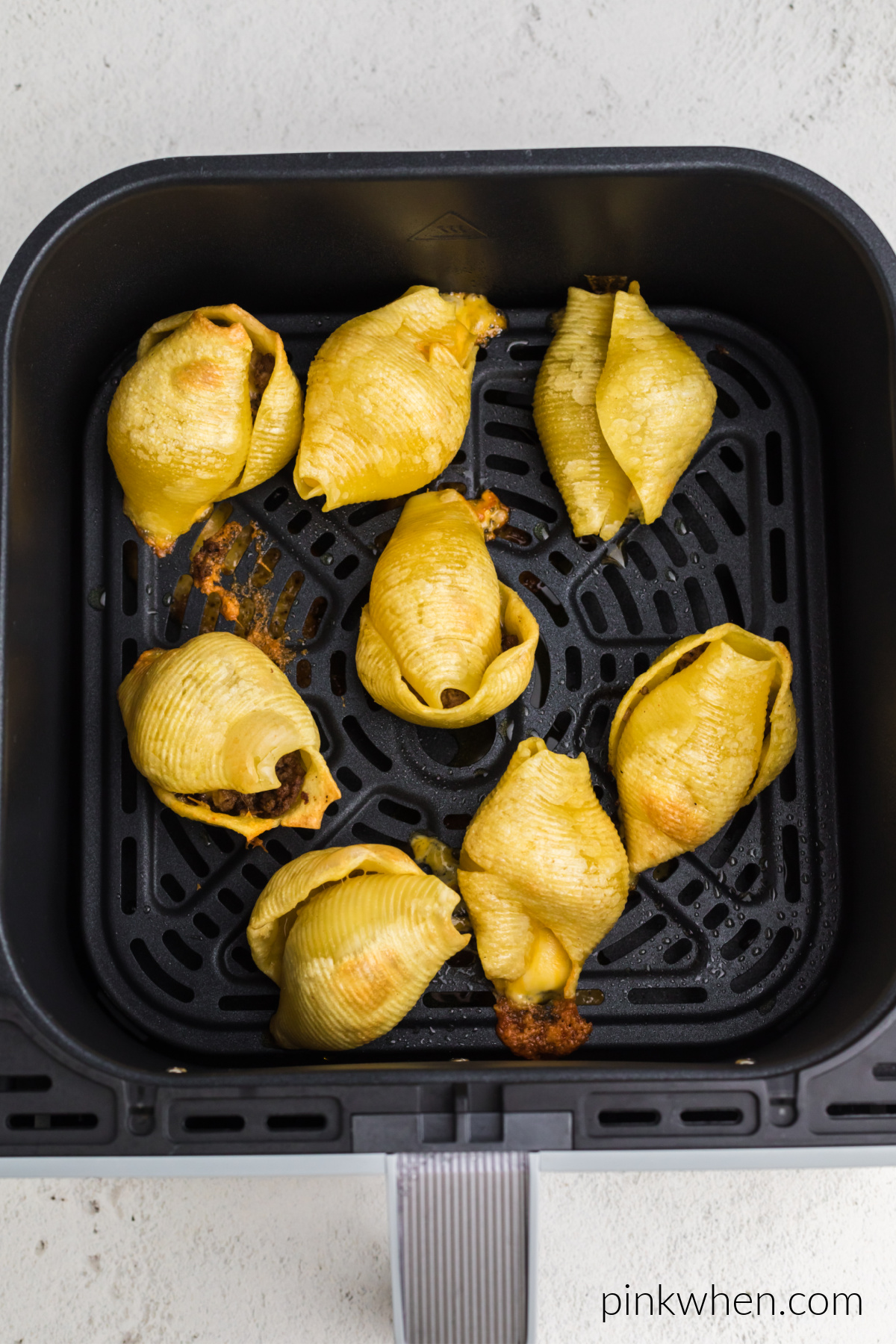 Air fried taco stuffed shells in the basket of the air fryer.