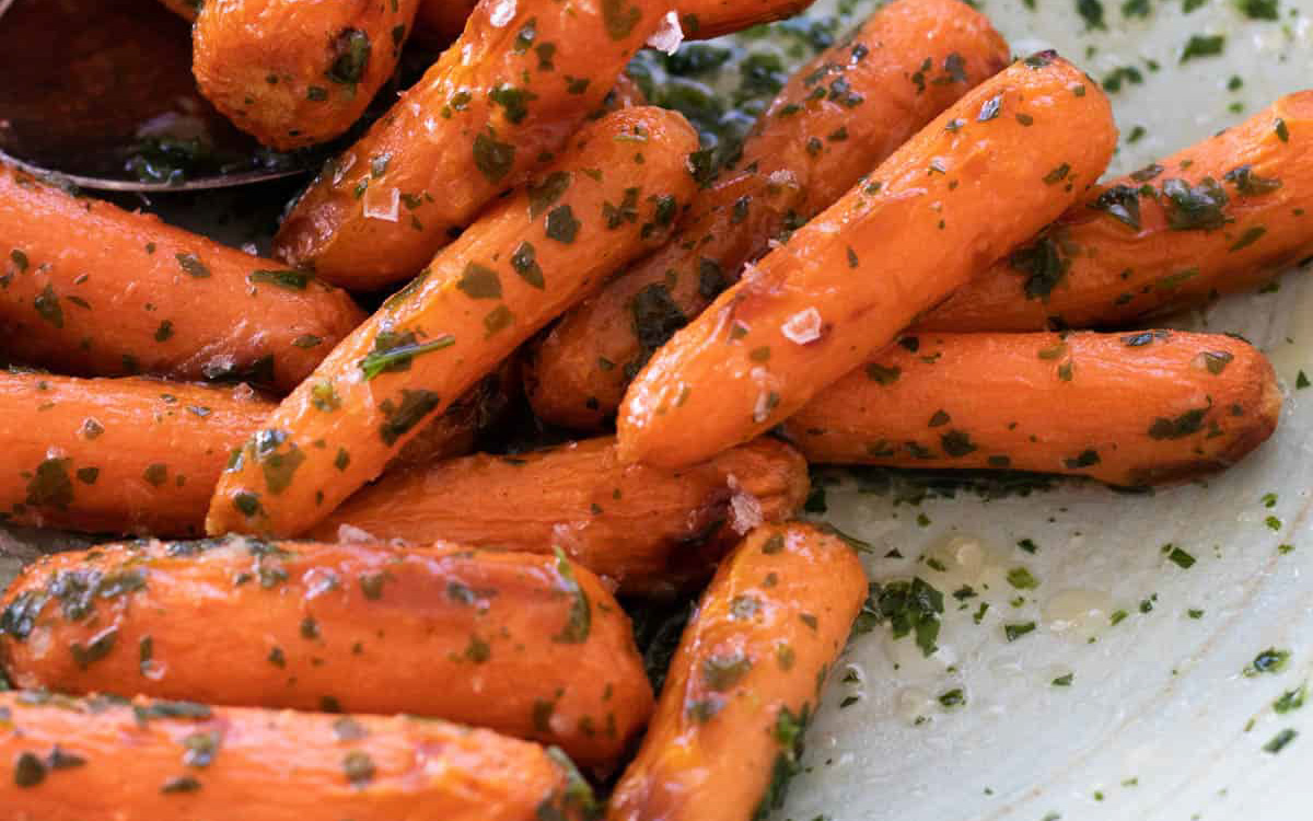 Baby carrots with herbs on a plate.