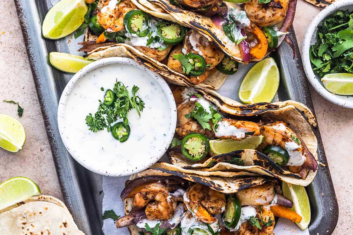 Grilled shrimp tacos on a tray with dipping sauce.