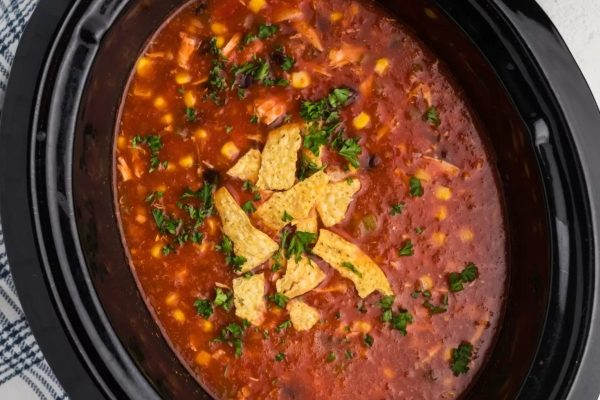 Chicken tortilla soup with tortilla chips and herbs.