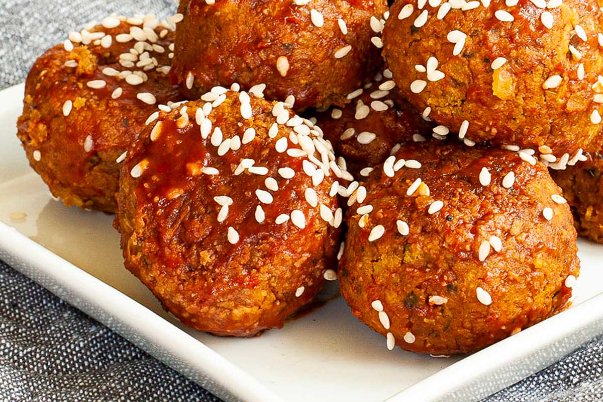 Chickpea meatballs with sesame seeds on top served with toothpicks.