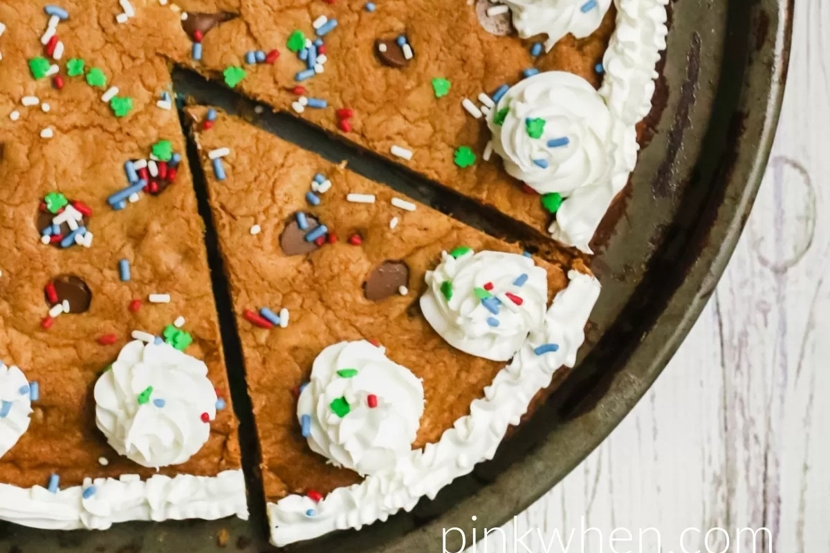 Chocolate chip cookie cake with whipped cream and sprinkles.