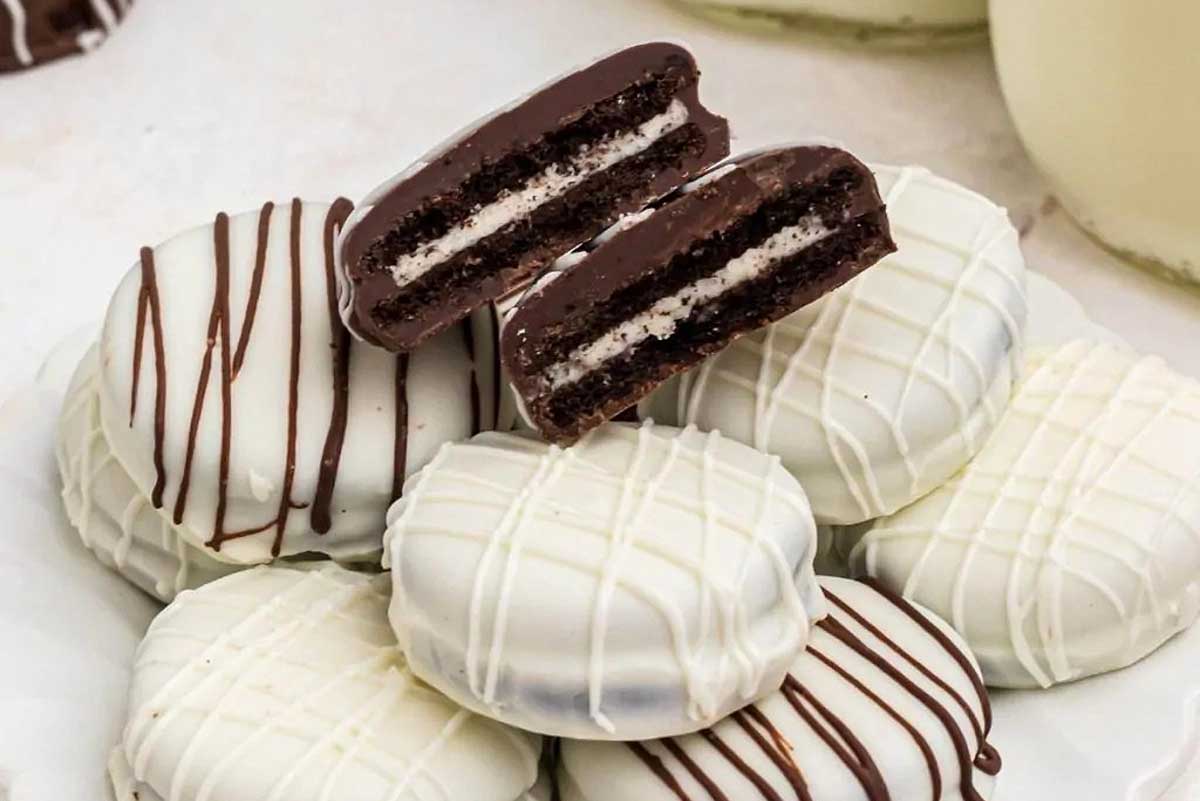 Chocolate covered oreos stacked up on a white plate.
