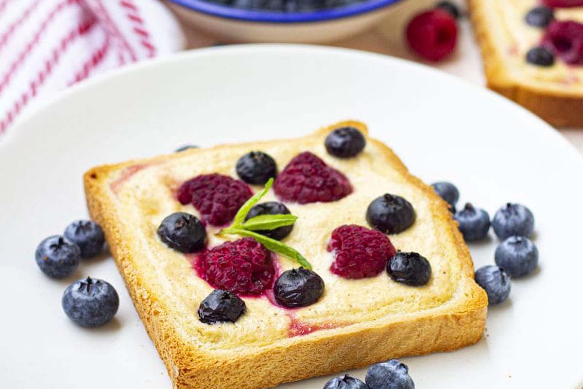 A toast with raspberries, blueberries and custard.