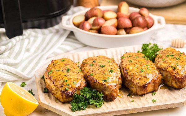 Pork chops on a wooden board with sauce.