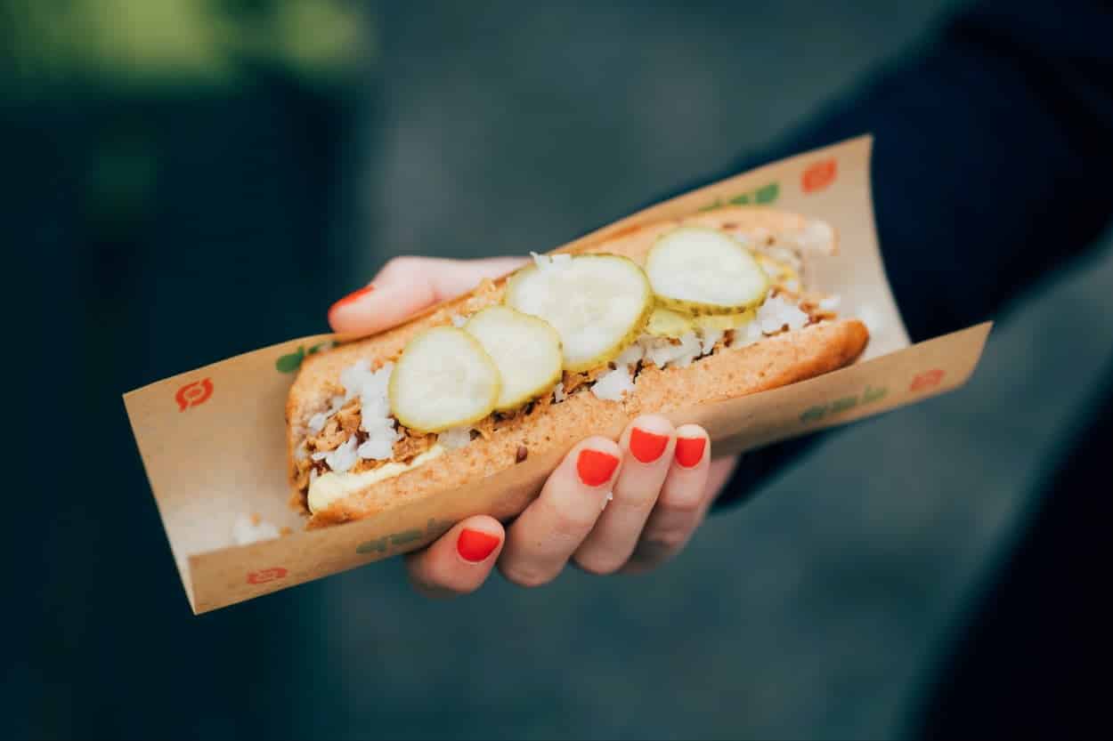 Denmark’s Rød Pølse on a brown paper held in a woman's hand.