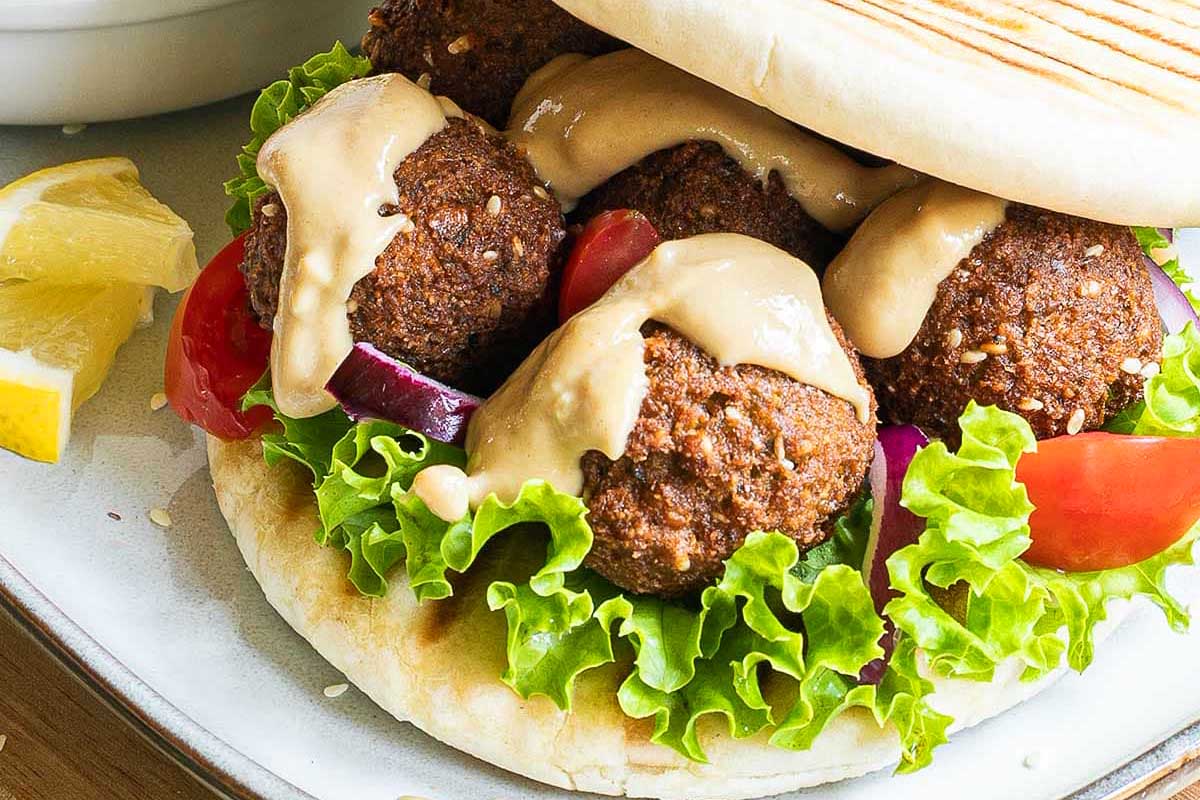 Falafel sandwich with lettuce, tomatoes and dressing.
