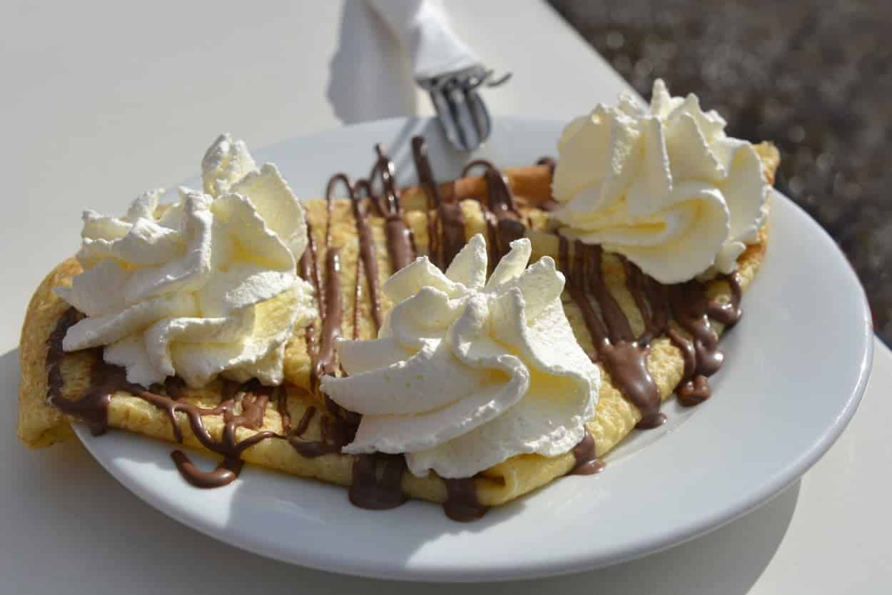 France’s Crepes on a white plate topped with whipped cream.