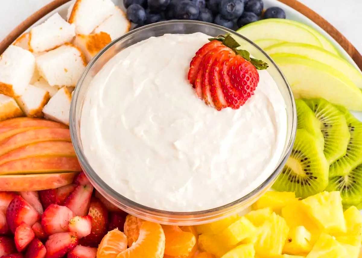 A round platter with a dip and fresh cut fruit.