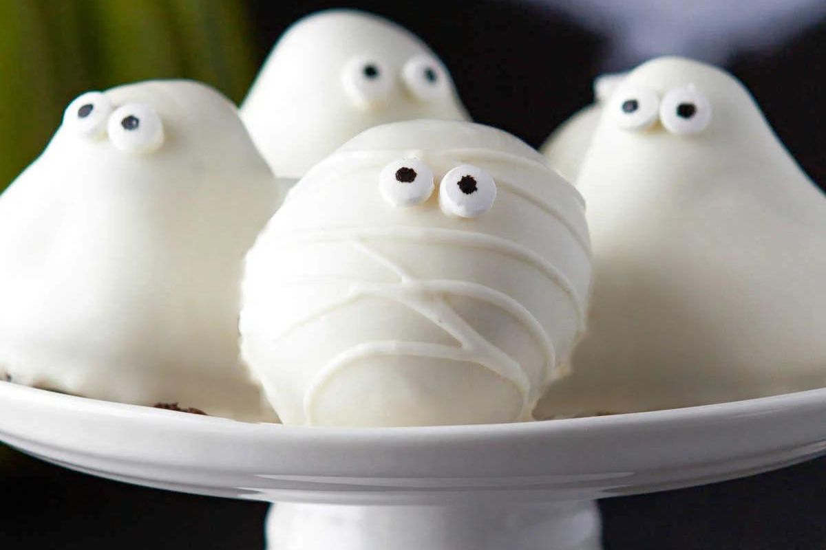 Oreo balls decorated to look like mummies and ghosts on a plate.