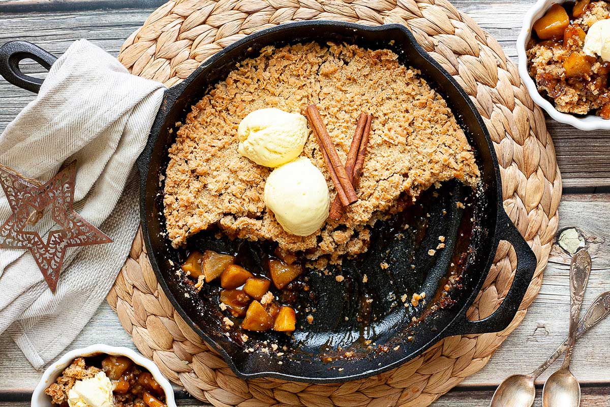 Apple crumble in cast iron skillet with scoops of ice cream.