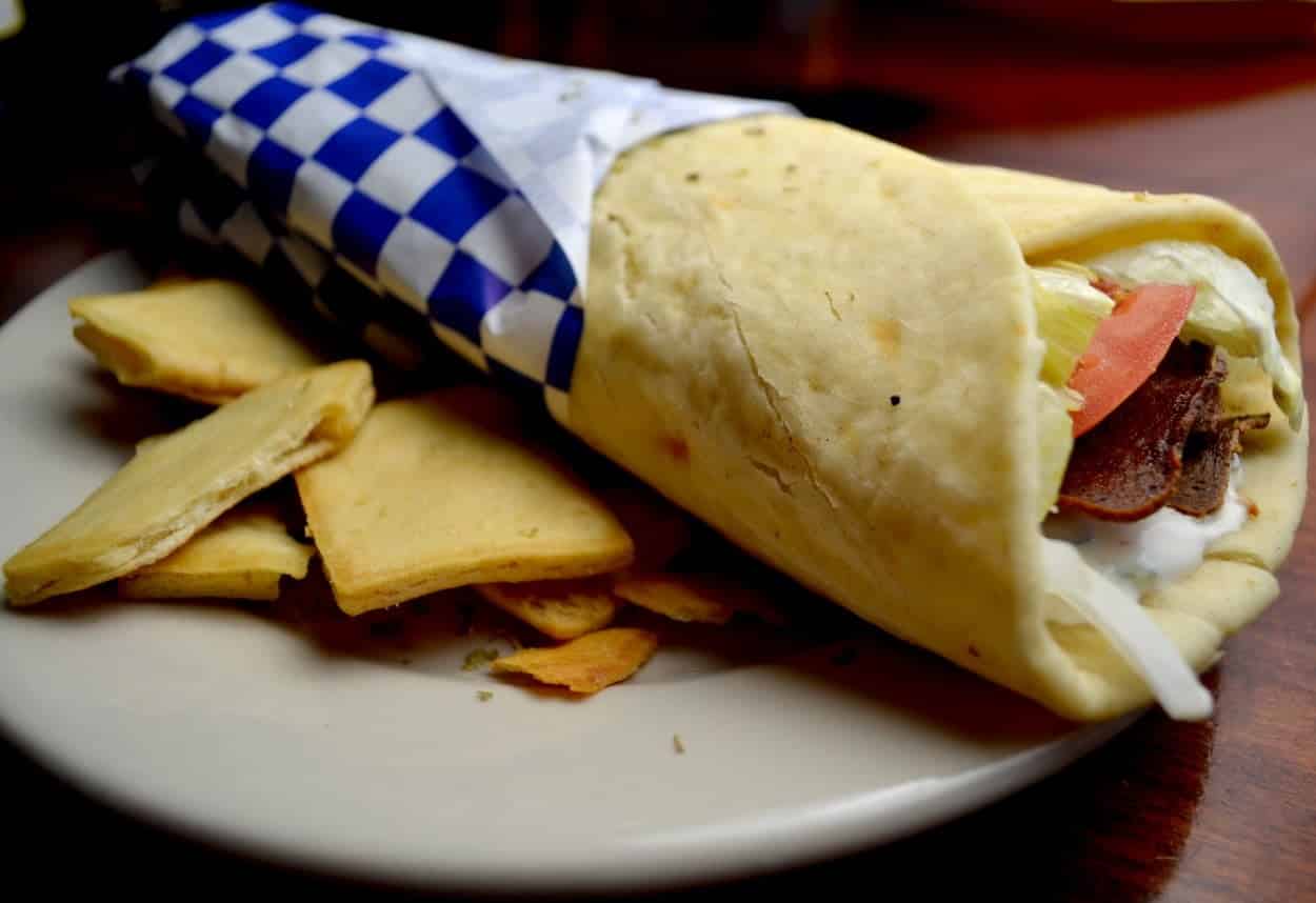 Greece’s Gyro wrapped in a pita on a white plate.