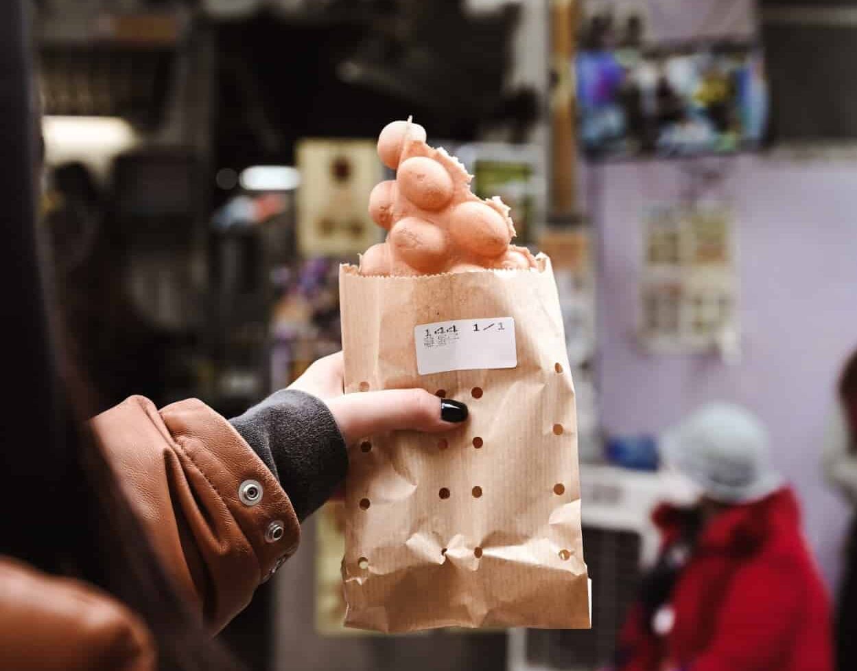 Hong Kong’s Egg Waffle in a brown paper bag held by a woman's hand.