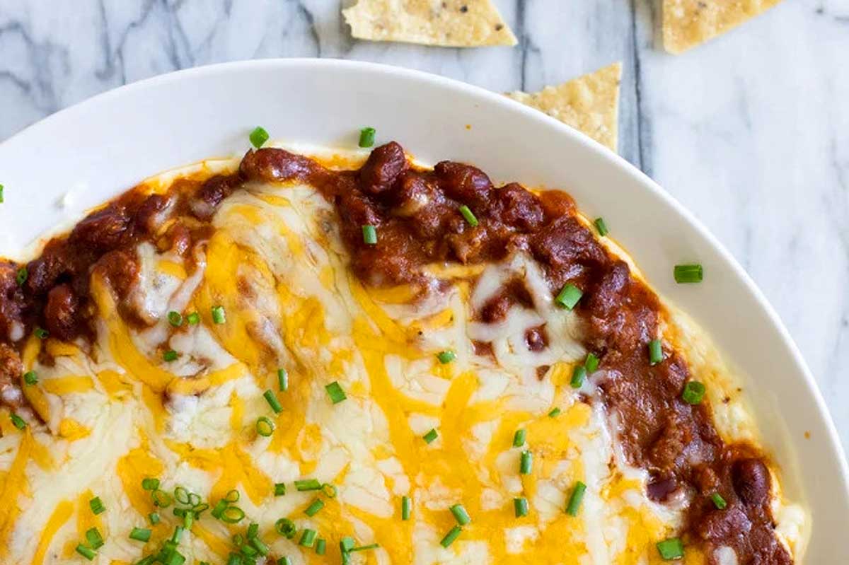 Chili cheese dip in a bowl with minced chives on top.