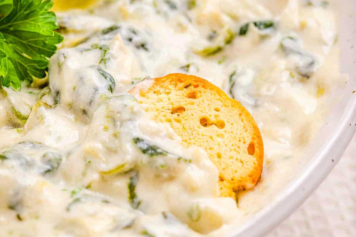 Creamy spinach artichoke dip served with toast rounds.