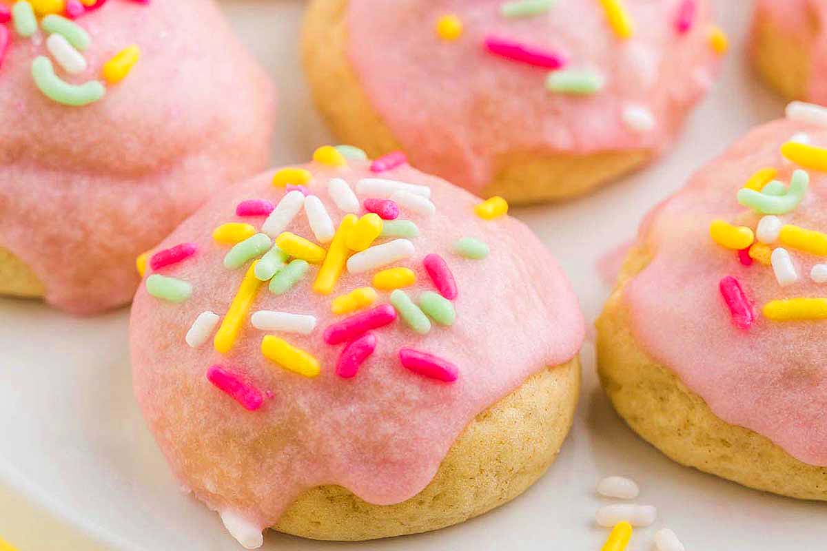Pink frosted cookies with multicolored sprinkles on top.